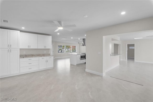 kitchen with ceiling fan, white cabinets, wall chimney range hood, and wall oven