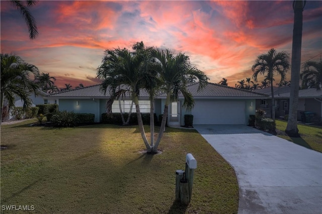 view of front of house featuring an attached garage, a tile roof, concrete driveway, stucco siding, and a front lawn