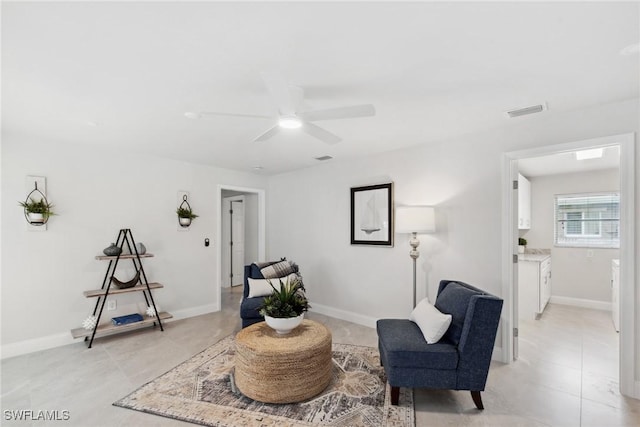 sitting room featuring a ceiling fan, visible vents, baseboards, and light tile patterned flooring