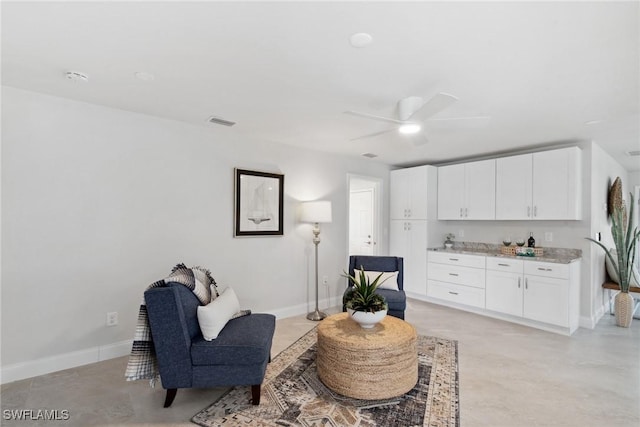 living area featuring finished concrete floors, visible vents, baseboards, and a ceiling fan