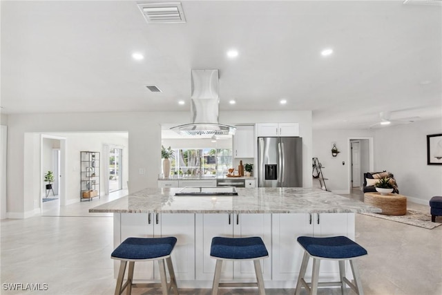 kitchen with a breakfast bar, island exhaust hood, appliances with stainless steel finishes, white cabinets, and light stone countertops