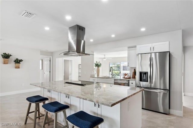 kitchen featuring island range hood, a sink, visible vents, white cabinetry, and appliances with stainless steel finishes