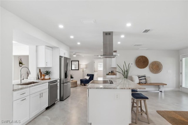 kitchen featuring island exhaust hood, stainless steel appliances, visible vents, white cabinets, and a sink