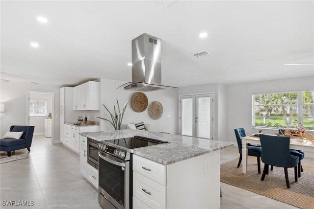 kitchen with island exhaust hood, appliances with stainless steel finishes, white cabinets, and a center island