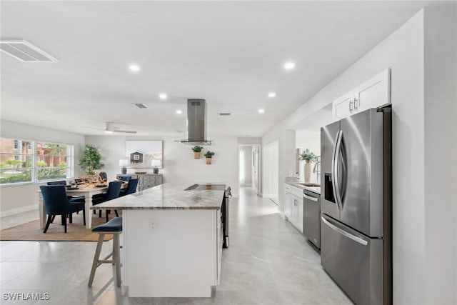 kitchen featuring island range hood, visible vents, white cabinets, appliances with stainless steel finishes, and a kitchen breakfast bar