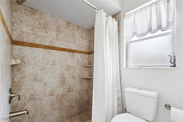 bathroom featuring tiled shower and toilet