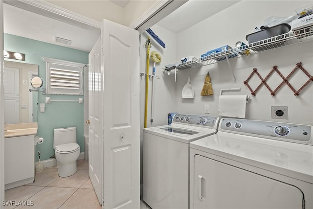 clothes washing area featuring light tile patterned flooring and washing machine and dryer