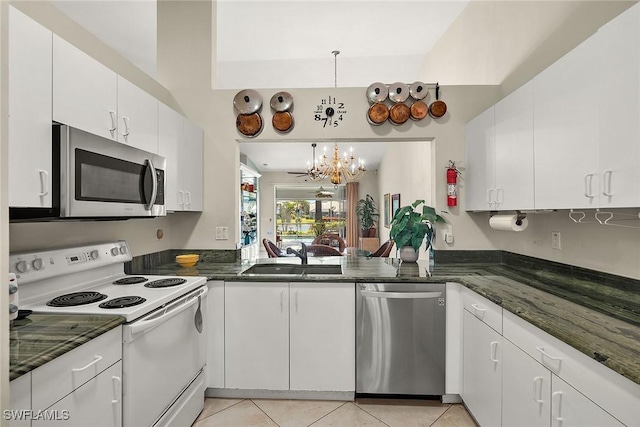 kitchen with sink, stainless steel appliances, light tile patterned floors, a chandelier, and white cabinets