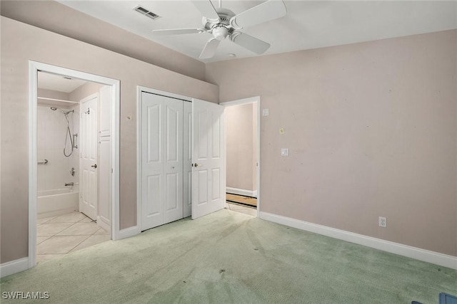 unfurnished bedroom with ensuite bath, ceiling fan, a closet, and light colored carpet