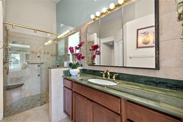 bathroom with tile patterned floors, tile walls, an enclosed shower, and vanity