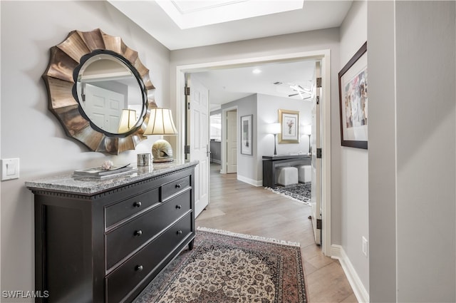 hallway with light hardwood / wood-style flooring and a skylight