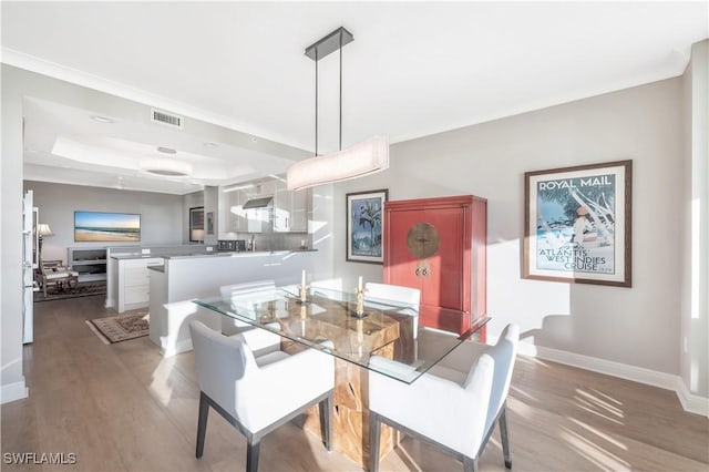 dining area featuring wood-type flooring, sink, and a tray ceiling