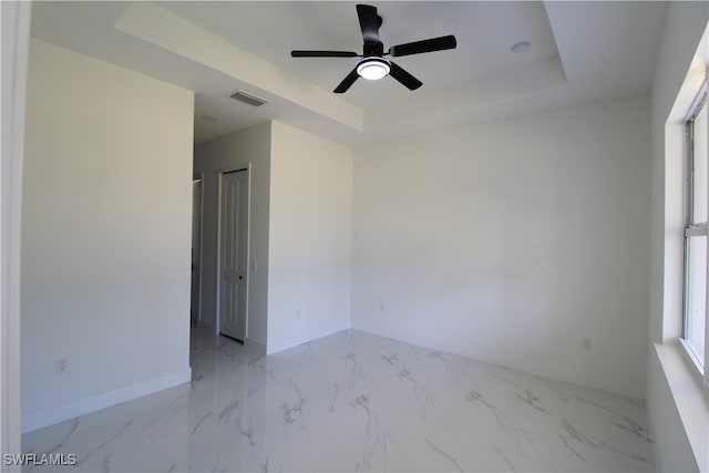 spare room with a tray ceiling and ceiling fan