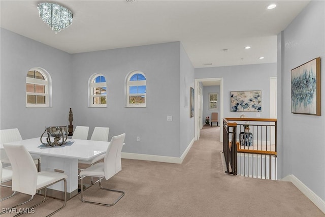 carpeted dining space with a notable chandelier