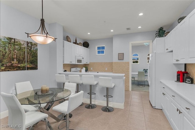 kitchen featuring light tile patterned floors, white appliances, white cabinets, and hanging light fixtures