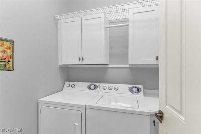 laundry room featuring washing machine and clothes dryer and cabinets