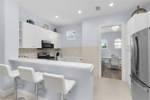 9219 Corfu Ct Unit 202, Naples, FL 34114 - kitchen with appliances with stainless steel finishes, a breakfast bar area, open shelves, light tile patterned floors, and recessed lighting