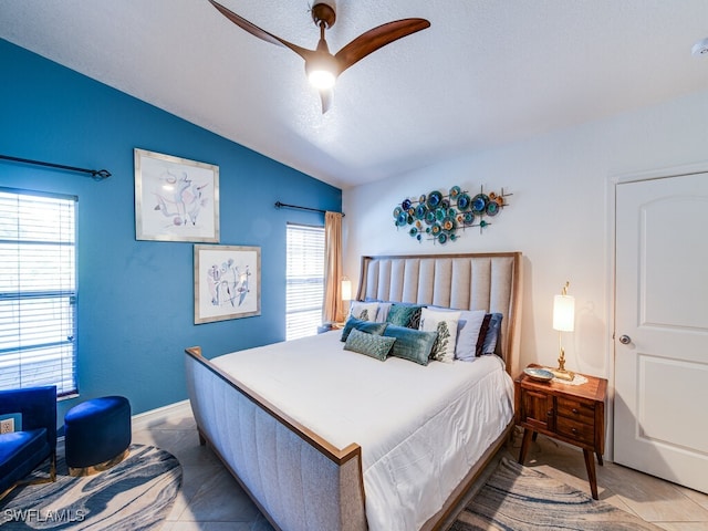 bedroom featuring a textured ceiling, ceiling fan, light tile patterned flooring, and lofted ceiling