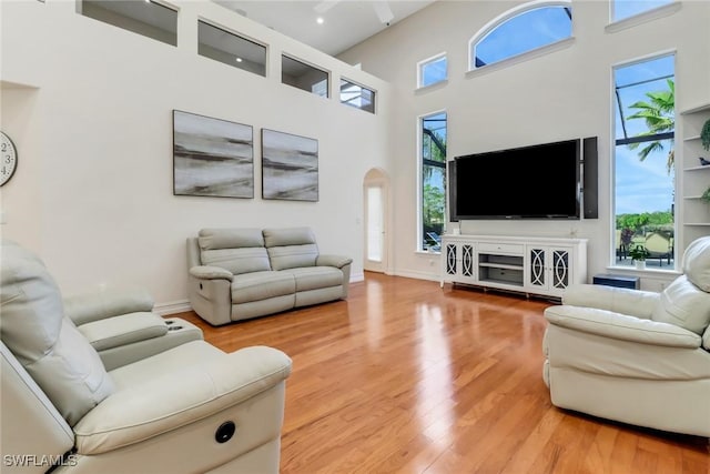 living room featuring a wealth of natural light, a towering ceiling, and hardwood / wood-style flooring