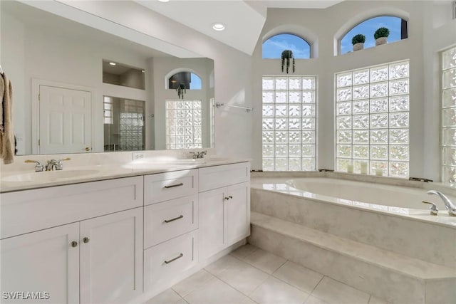 bathroom with tiled tub, tile patterned flooring, and vanity