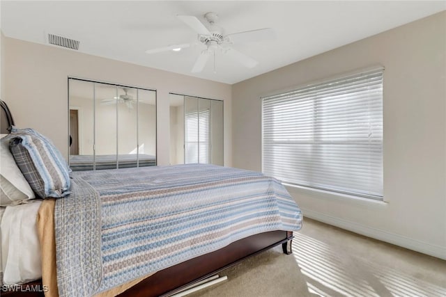 bedroom with ceiling fan, carpet floors, and two closets