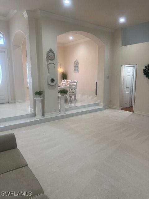 unfurnished living room featuring light colored carpet and ornamental molding