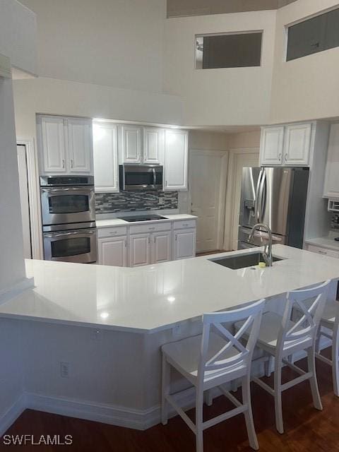 kitchen featuring white cabinets, stainless steel appliances, a breakfast bar area, and sink