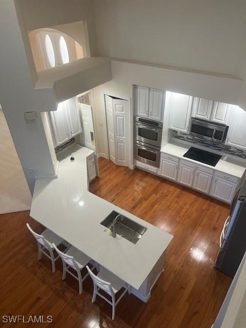 kitchen featuring white cabinets, decorative backsplash, black cooktop, and dark wood-type flooring