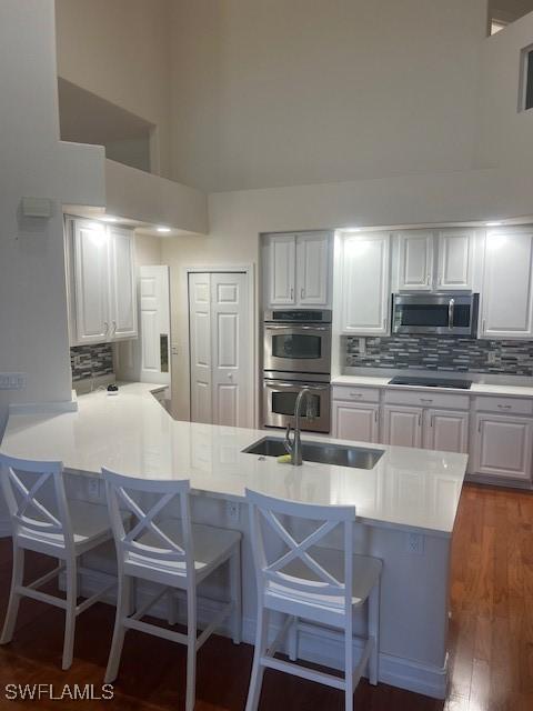 kitchen featuring a kitchen breakfast bar, white cabinetry, kitchen peninsula, and appliances with stainless steel finishes