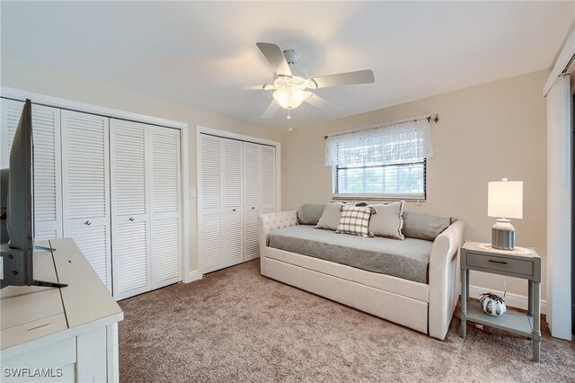 bedroom with ceiling fan, light carpet, and multiple closets