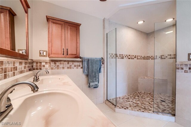 bathroom with tile patterned flooring, tiled shower, and sink