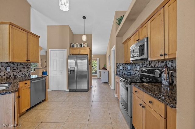 kitchen featuring light tile patterned floors, hanging light fixtures, decorative backsplash, appliances with stainless steel finishes, and dark stone countertops