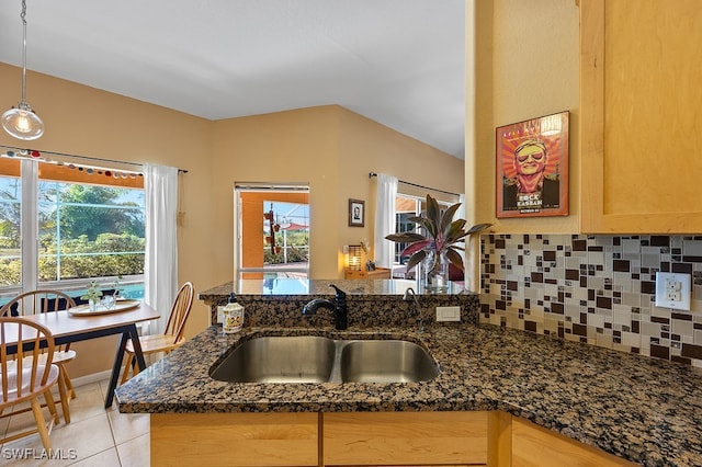 kitchen with decorative backsplash, sink, a wealth of natural light, and dark stone counters