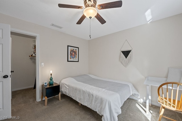 bedroom featuring a walk in closet, carpet floors, and ceiling fan