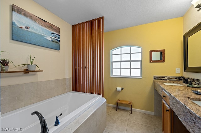 bathroom with tile patterned floors, vanity, a textured ceiling, and tiled bath