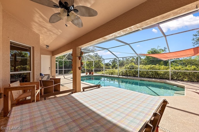 view of pool featuring a patio, glass enclosure, and ceiling fan