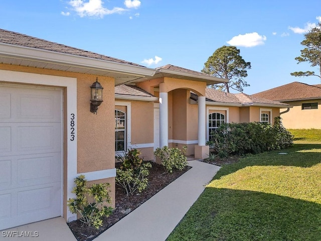 view of exterior entry with a yard, an attached garage, and stucco siding