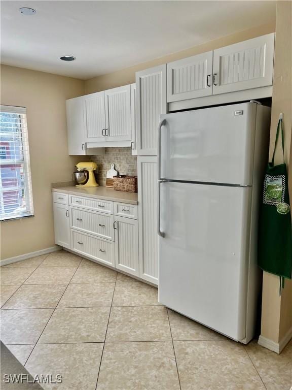 kitchen featuring decorative backsplash, white fridge, white cabinetry, and light tile patterned floors