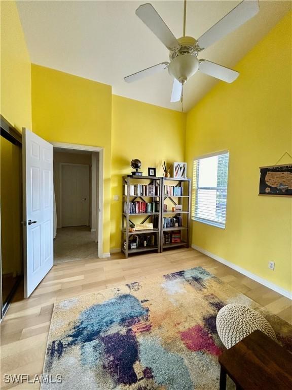 living area with ceiling fan, vaulted ceiling, and light wood-type flooring