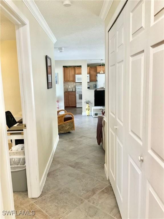 hall with ornamental molding and a textured ceiling