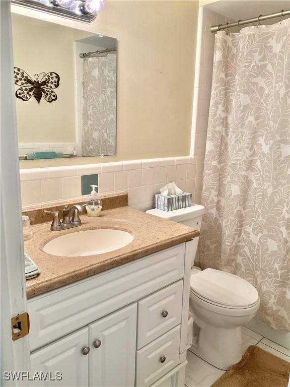 bathroom with tile walls, vanity, and toilet