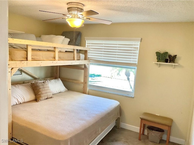 tiled bedroom with ceiling fan and a textured ceiling