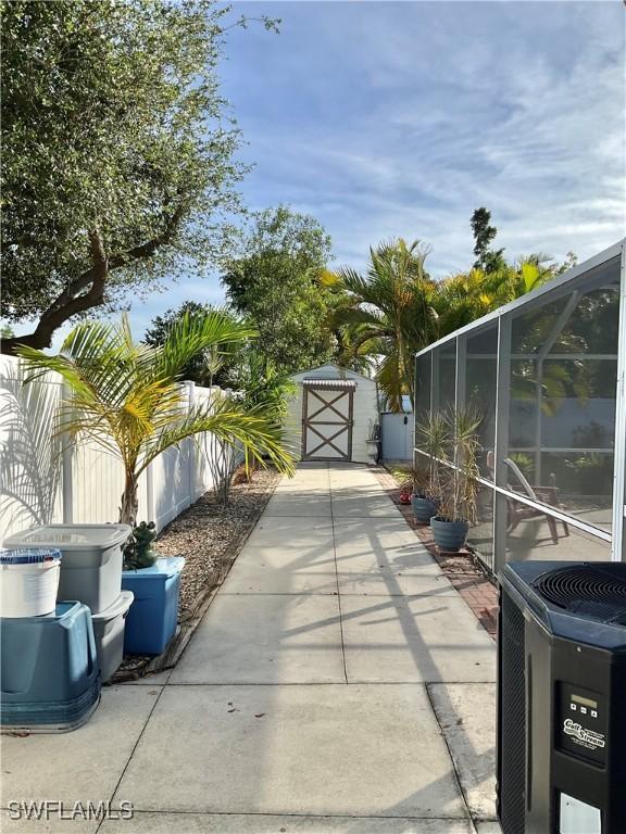 view of patio with central AC, a storage unit, and glass enclosure