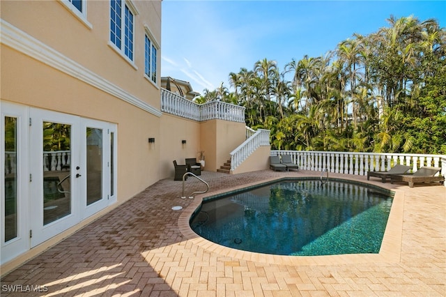 view of swimming pool with french doors and a patio