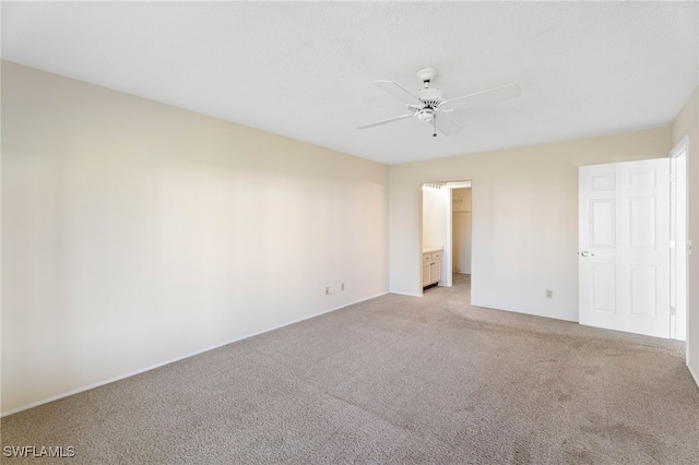 unfurnished bedroom with a spacious closet, a closet, ceiling fan, and light carpet