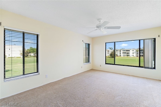 carpeted empty room with ceiling fan and a textured ceiling