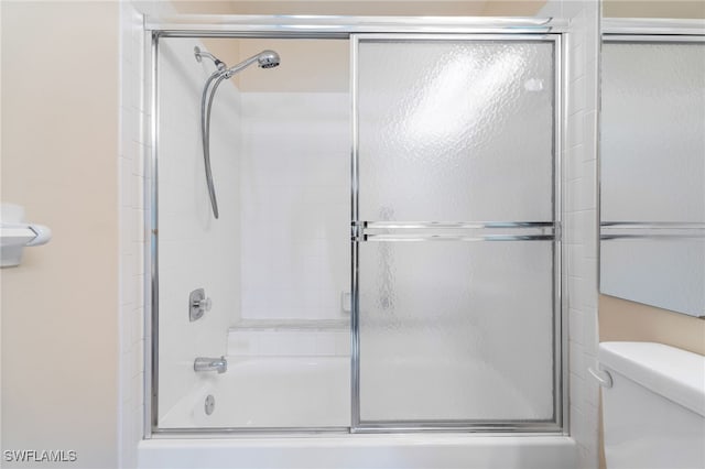 bathroom featuring combined bath / shower with glass door and toilet