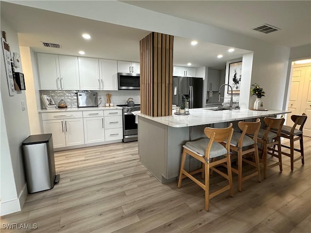 kitchen with sink, a breakfast bar, white cabinets, and appliances with stainless steel finishes