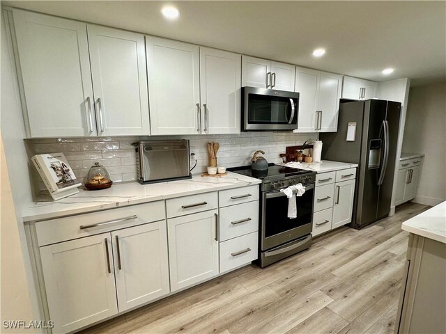 1900 Clifford St Unit 201, Fort Myers, FL 33901 - kitchen with stainless steel appliances, white cabinets, light wood-style flooring, decorative backsplash, and recessed lighting