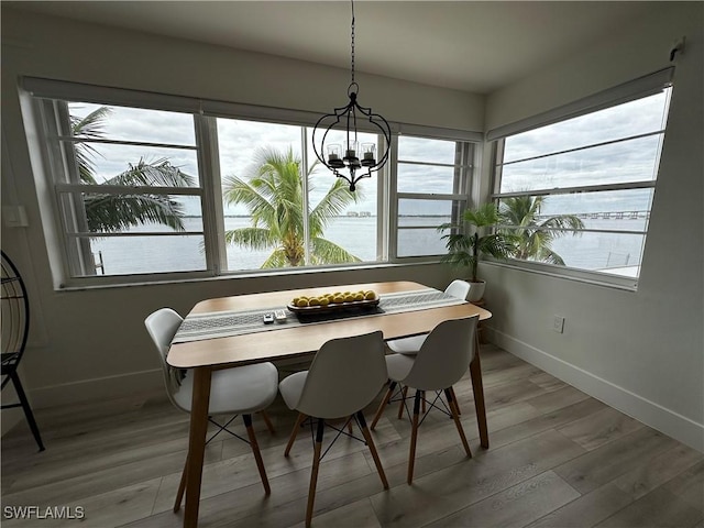 dining area featuring hardwood / wood-style floors, a water view, and an inviting chandelier